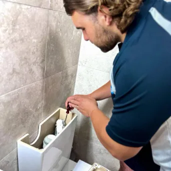 A plumber fitting a new cistern under a bathroom sink